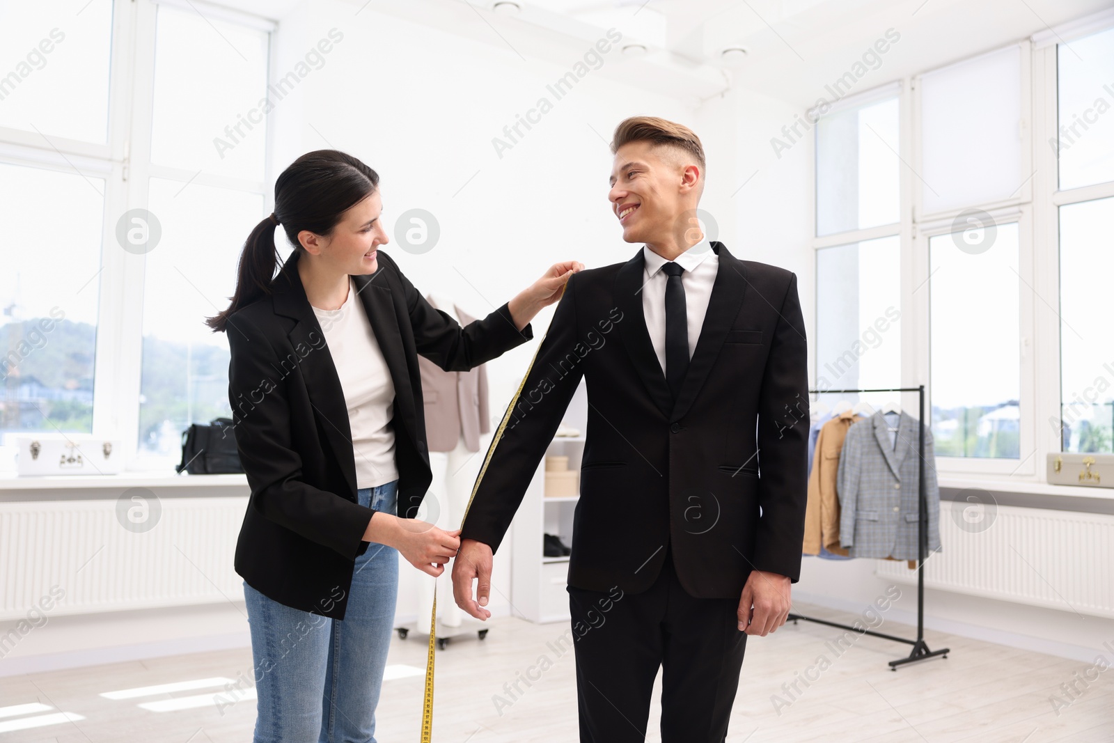 Photo of Tailor measuring jacket on man in atelier
