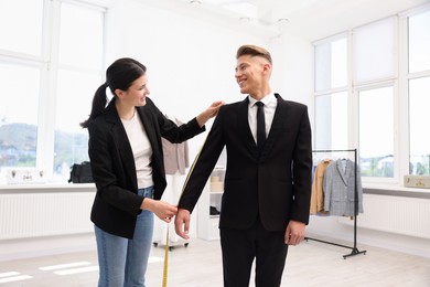 Photo of Tailor measuring jacket on man in atelier