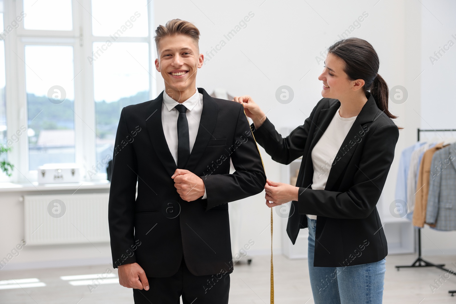 Photo of Tailor measuring jacket on man in atelier