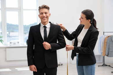 Photo of Tailor measuring jacket on man in atelier