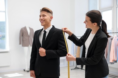 Photo of Tailor measuring jacket on man in atelier
