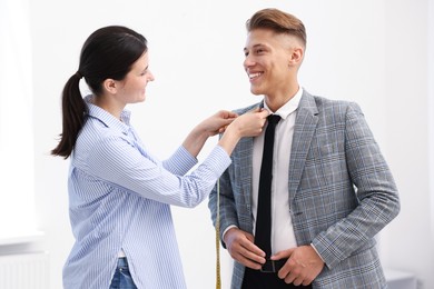 Photo of Tailor measuring jacket on man in atelier