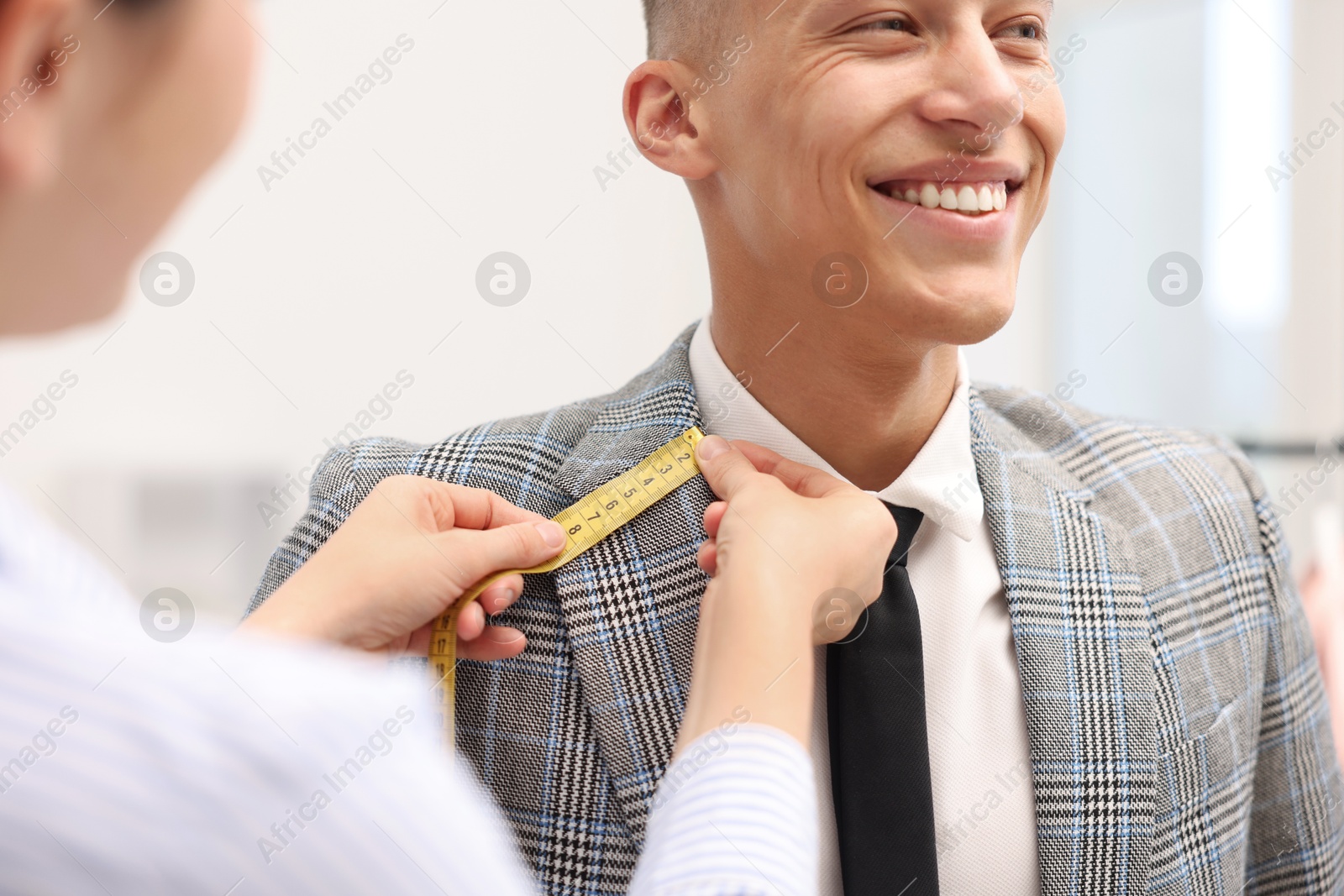 Tailor measuring jacket on man in atelier, closeup Photo of Tailor measuring jacket on man in atelier, closeup