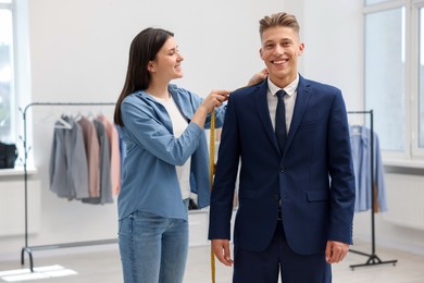 Photo of Tailor measuring jacket on man in atelier