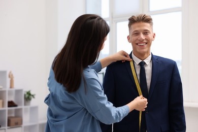 Photo of Tailor measuring jacket on man in atelier