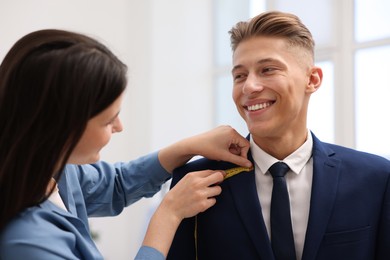 Photo of Tailor measuring jacket on man in atelier