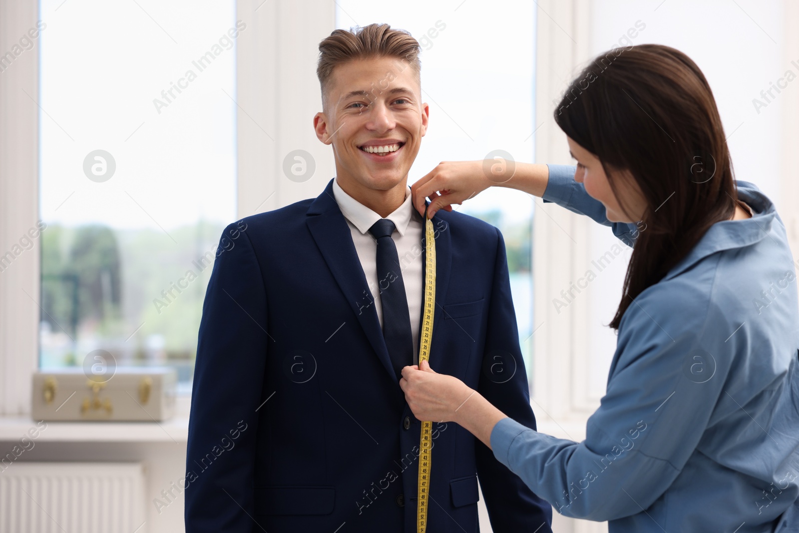 Photo of Tailor measuring jacket on man in atelier