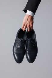 Photo of Man wearing pair of black leather shoes on light background, closeup