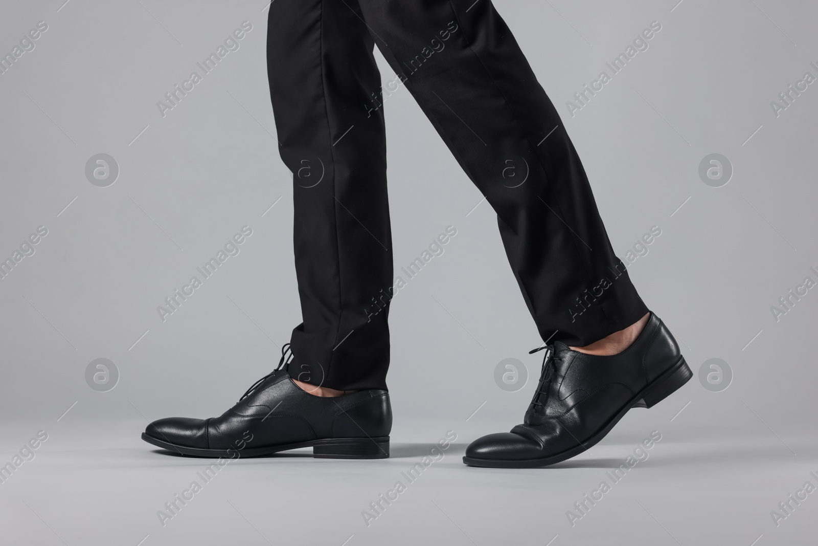 Photo of Man wearing pair of black leather shoes on light background, closeup