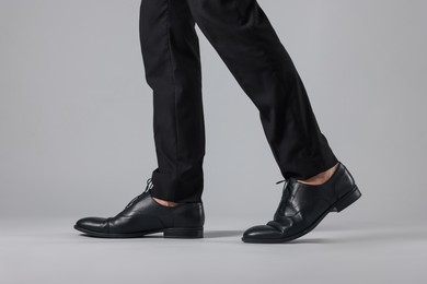 Photo of Man wearing pair of black leather shoes on light background, closeup