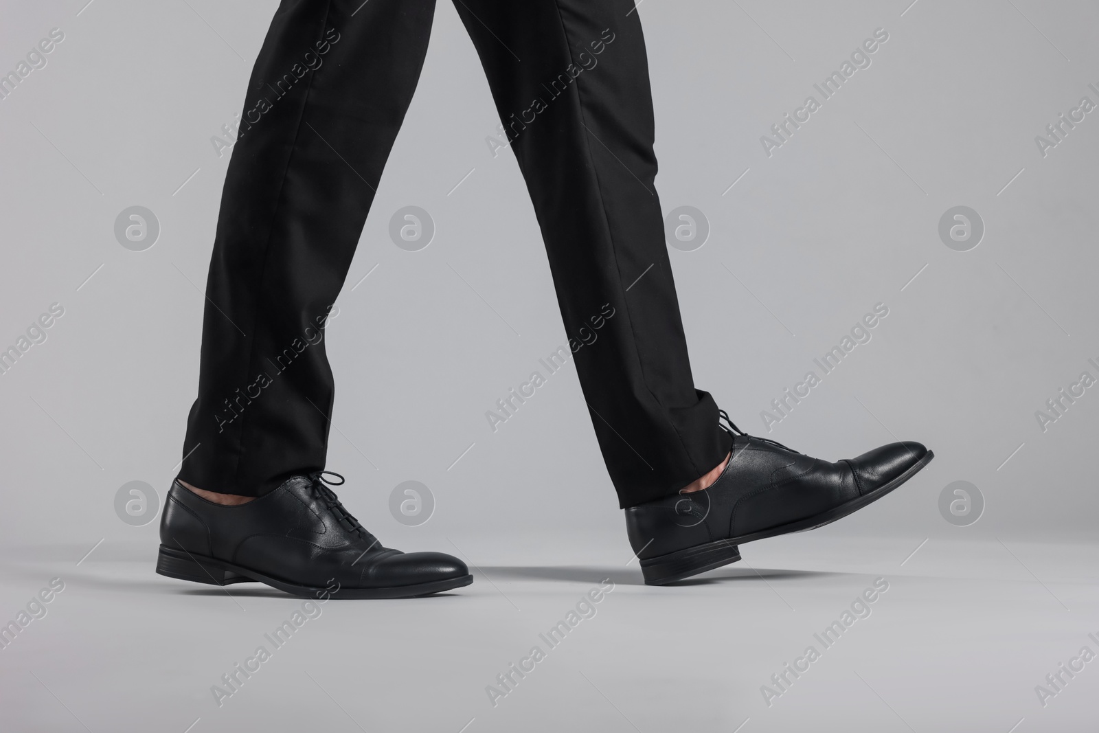Photo of Man wearing pair of black leather shoes on light background, closeup