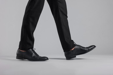 Photo of Man wearing pair of black leather shoes on light background, closeup