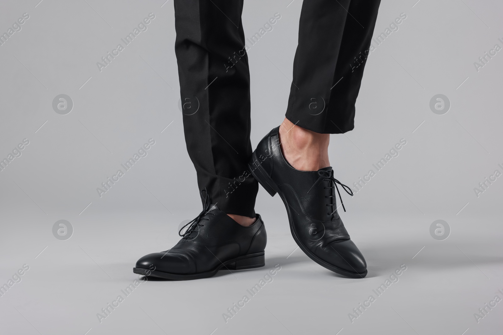 Photo of Man wearing pair of black leather shoes on light background, closeup