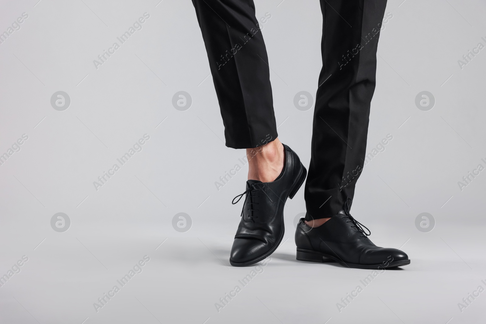 Photo of Man wearing pair of black leather shoes on light background, closeup. Space for text