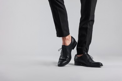 Photo of Man wearing pair of black leather shoes on light background, closeup. Space for text