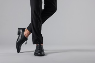 Photo of Man wearing pair of black leather shoes on light background, closeup. Space for text
