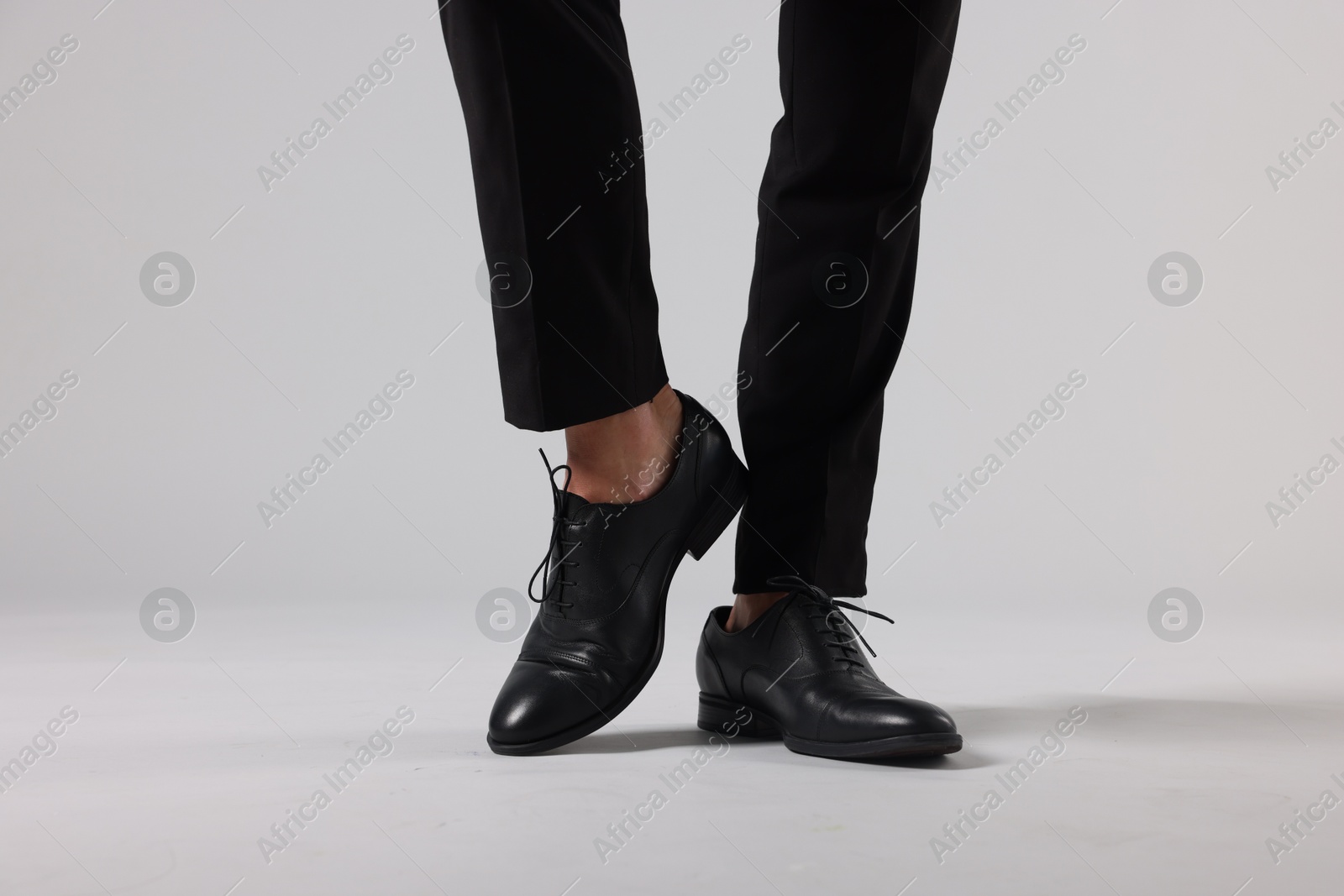 Photo of Man wearing pair of black leather shoes on light background, closeup
