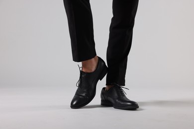 Photo of Man wearing pair of black leather shoes on light background, closeup
