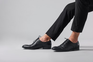 Photo of Man wearing pair of black leather shoes on light background, closeup. Space for text