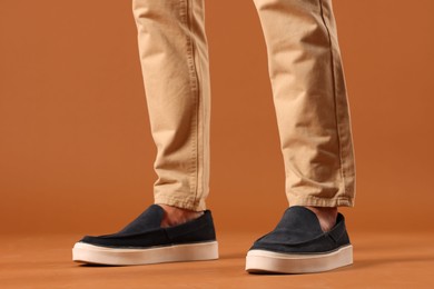 Photo of Man wearing pair of dark blue shoes on brown background, closeup