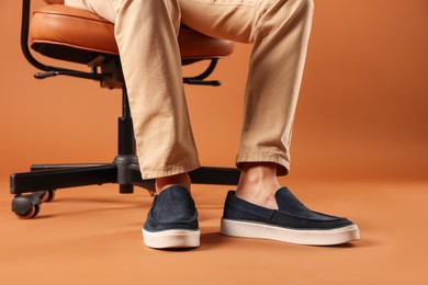 Photo of Man wearing pair of dark blue shoes on brown background, closeup