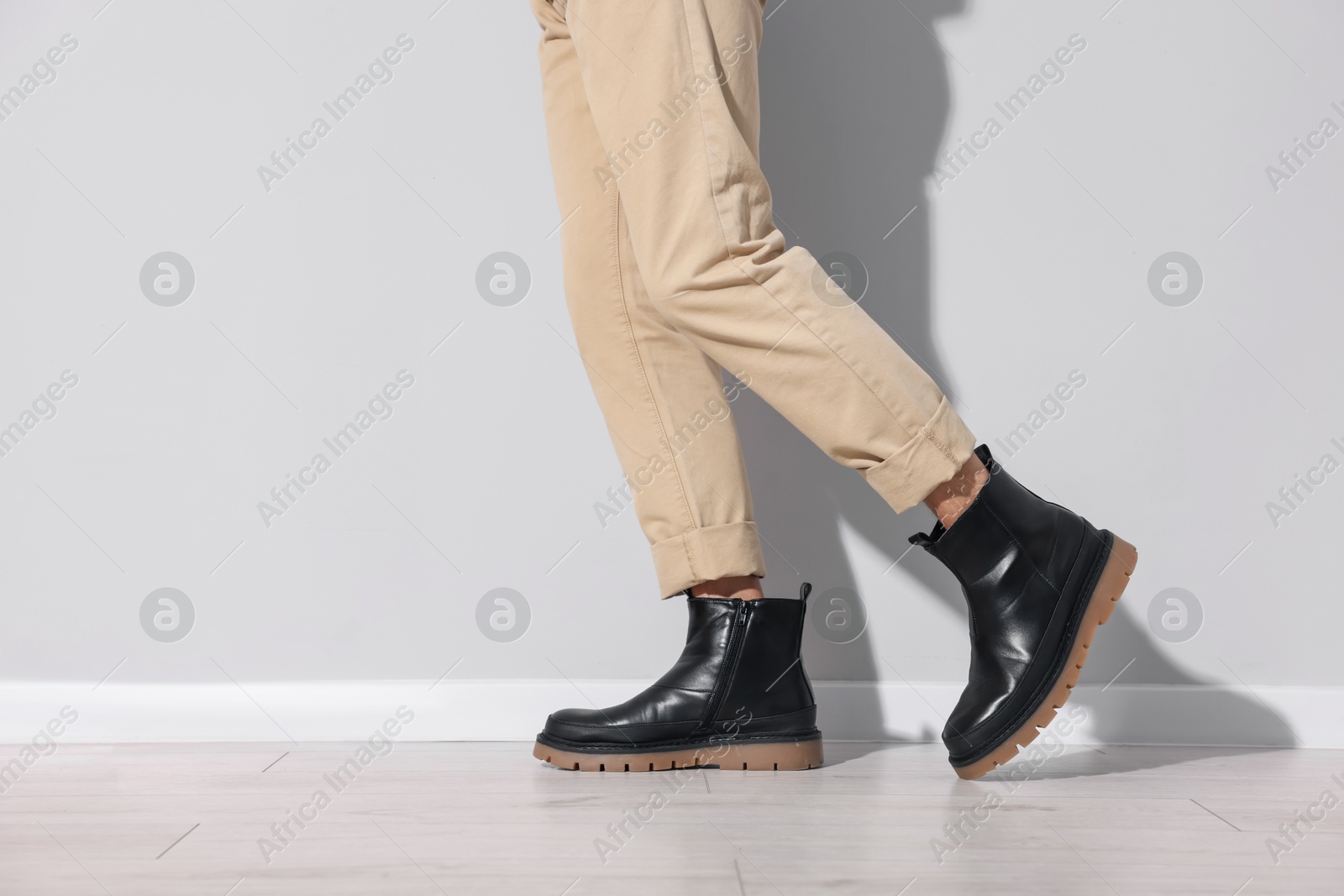 Photo of Man wearing pair of boots indoors, closeup. Space for text