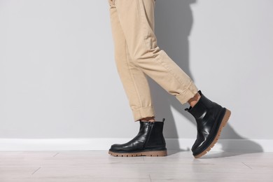 Photo of Man wearing pair of boots indoors, closeup. Space for text