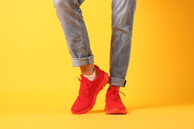 Photo of Man wearing pair of red sneakers on yellow background, closeup