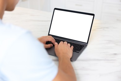 Photo of Man using laptop at white marble table indoors, closeup