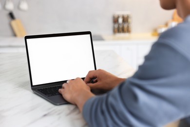 Photo of Man using laptop at white marble table indoors, closeup