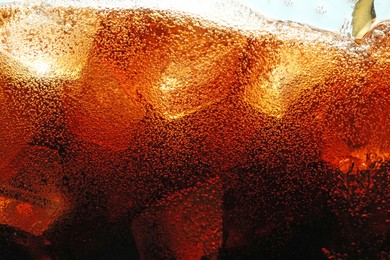 Photo of Fizzy cola with ice as background, macro view