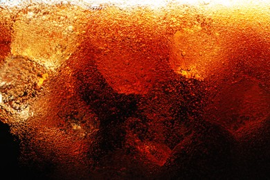 Photo of Fizzy cola with ice as background, macro view