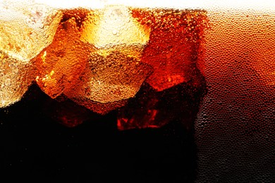Photo of Fizzy cola with ice as background, macro view