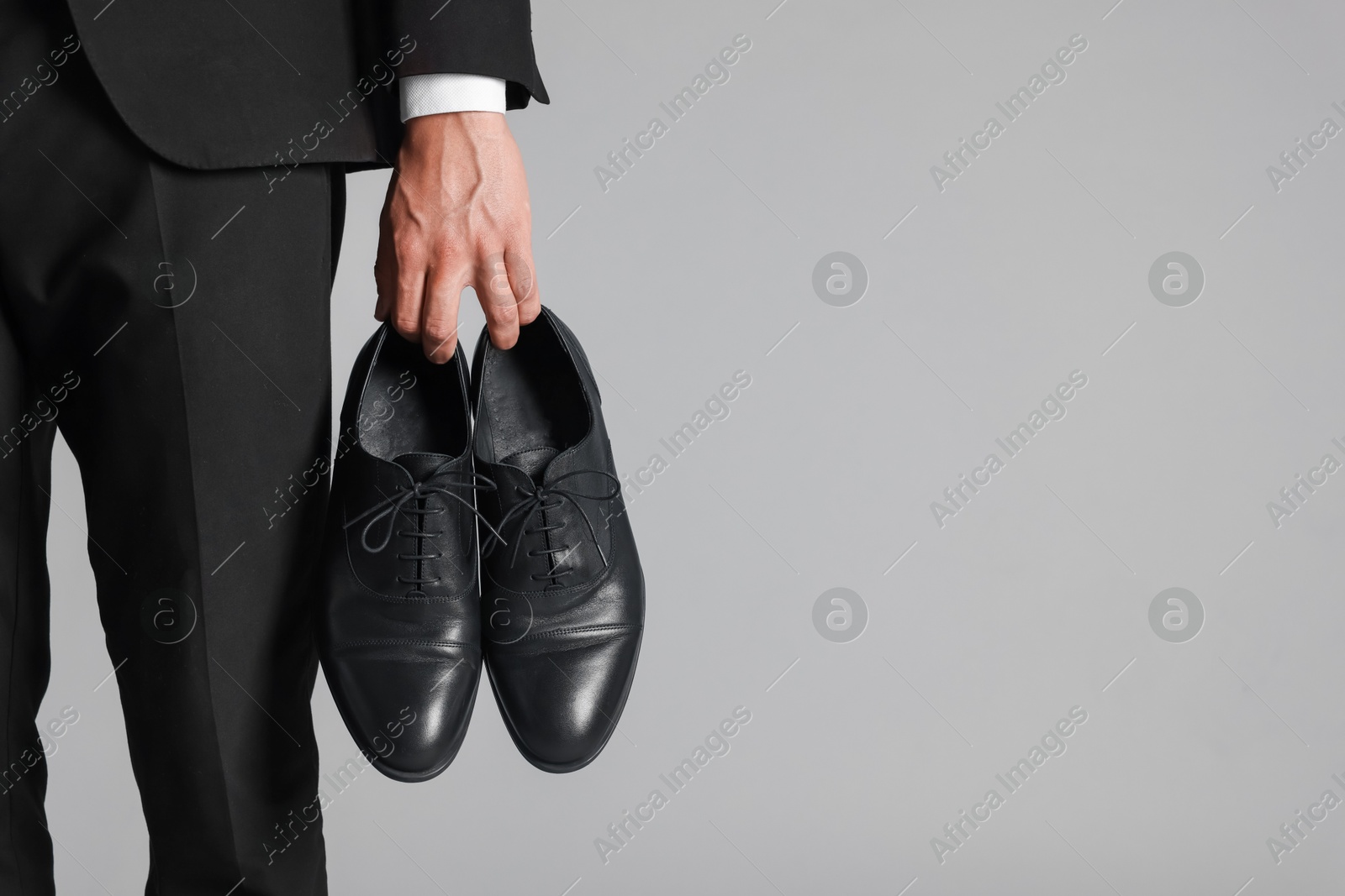 Photo of Man wearing pair of black leather shoes on light background, closeup. Space for text