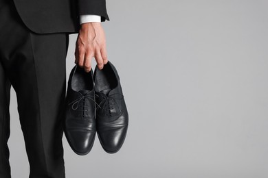 Photo of Man wearing pair of black leather shoes on light background, closeup. Space for text