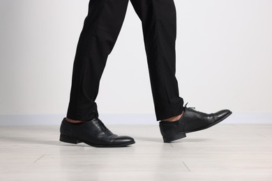 Photo of Man wearing pair of black leather shoes indoors, closeup