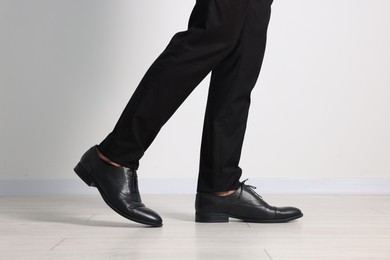 Photo of Man wearing pair of black leather shoes indoors, closeup