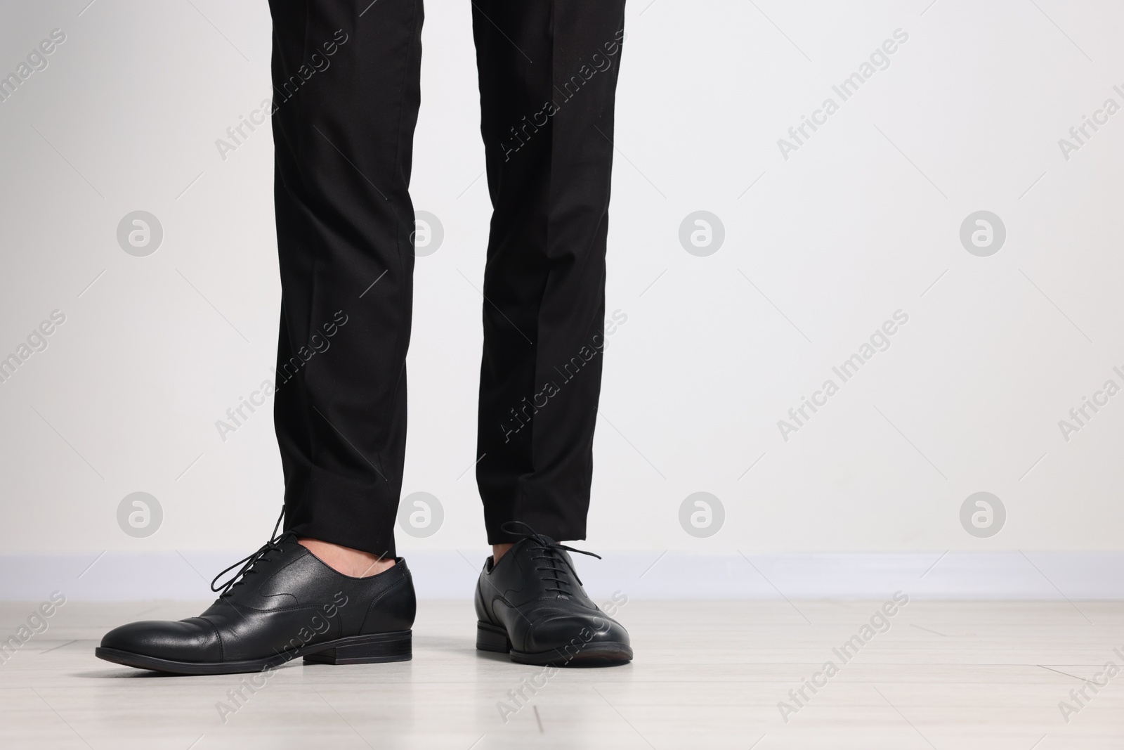 Man wearing pair of black leather shoes indoors, closeup. Space for text Photo of Man wearing pair of black leather shoes indoors, closeup. Space for text