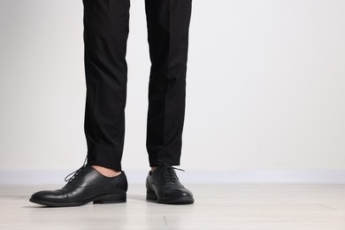 Photo of Man wearing pair of black leather shoes indoors, closeup. Space for text