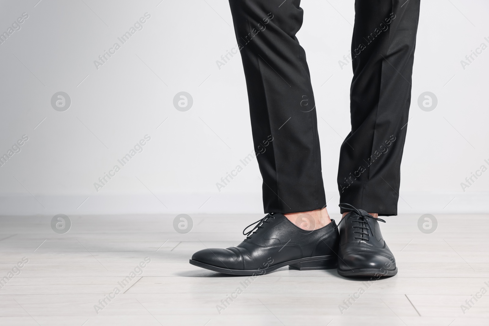Photo of Man wearing pair of black leather shoes indoors, closeup. Space for text
