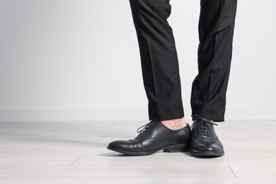 Photo of Man wearing pair of black leather shoes indoors, closeup. Space for text