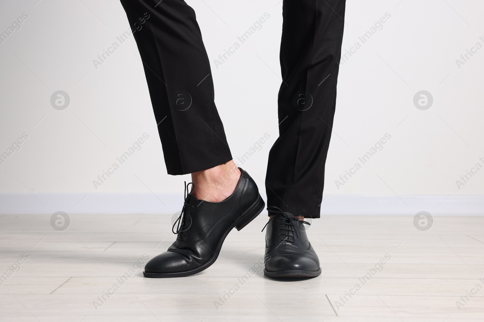 Photo of Man wearing pair of black leather shoes indoors, closeup