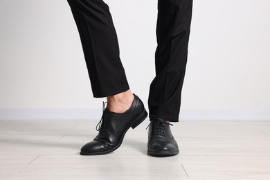 Photo of Man wearing pair of black leather shoes indoors, closeup