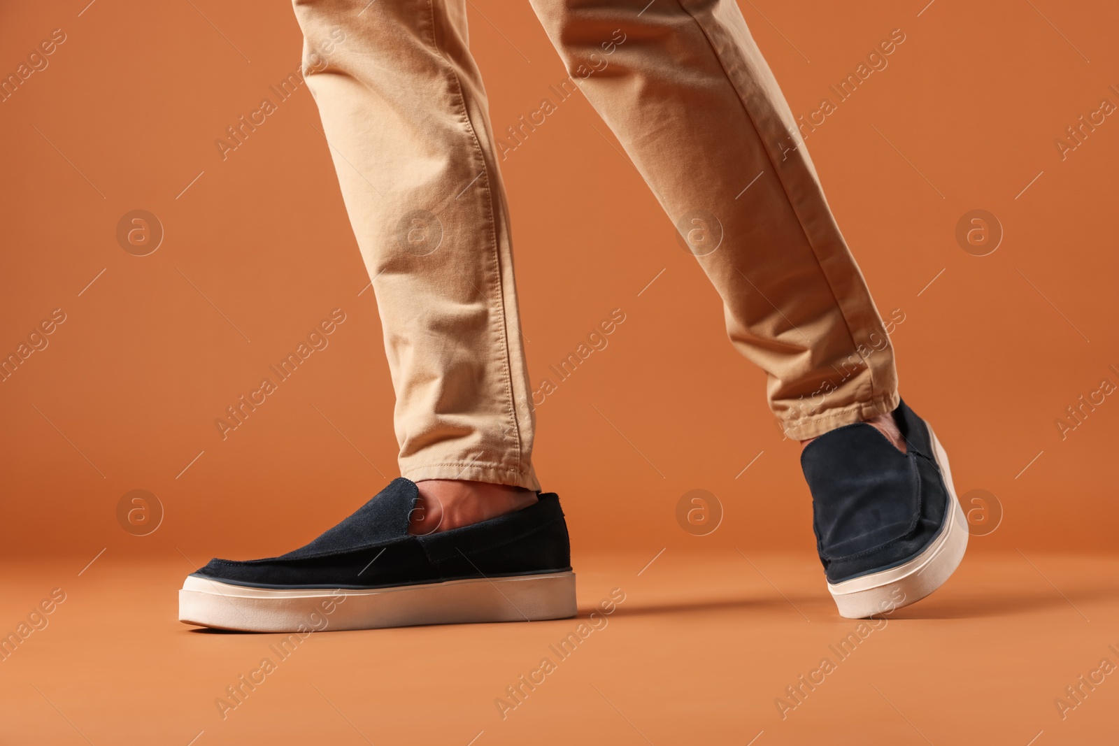 Photo of Man wearing pair of dark blue shoes on brown background, closeup