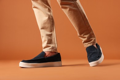 Photo of Man wearing pair of dark blue shoes on brown background, closeup