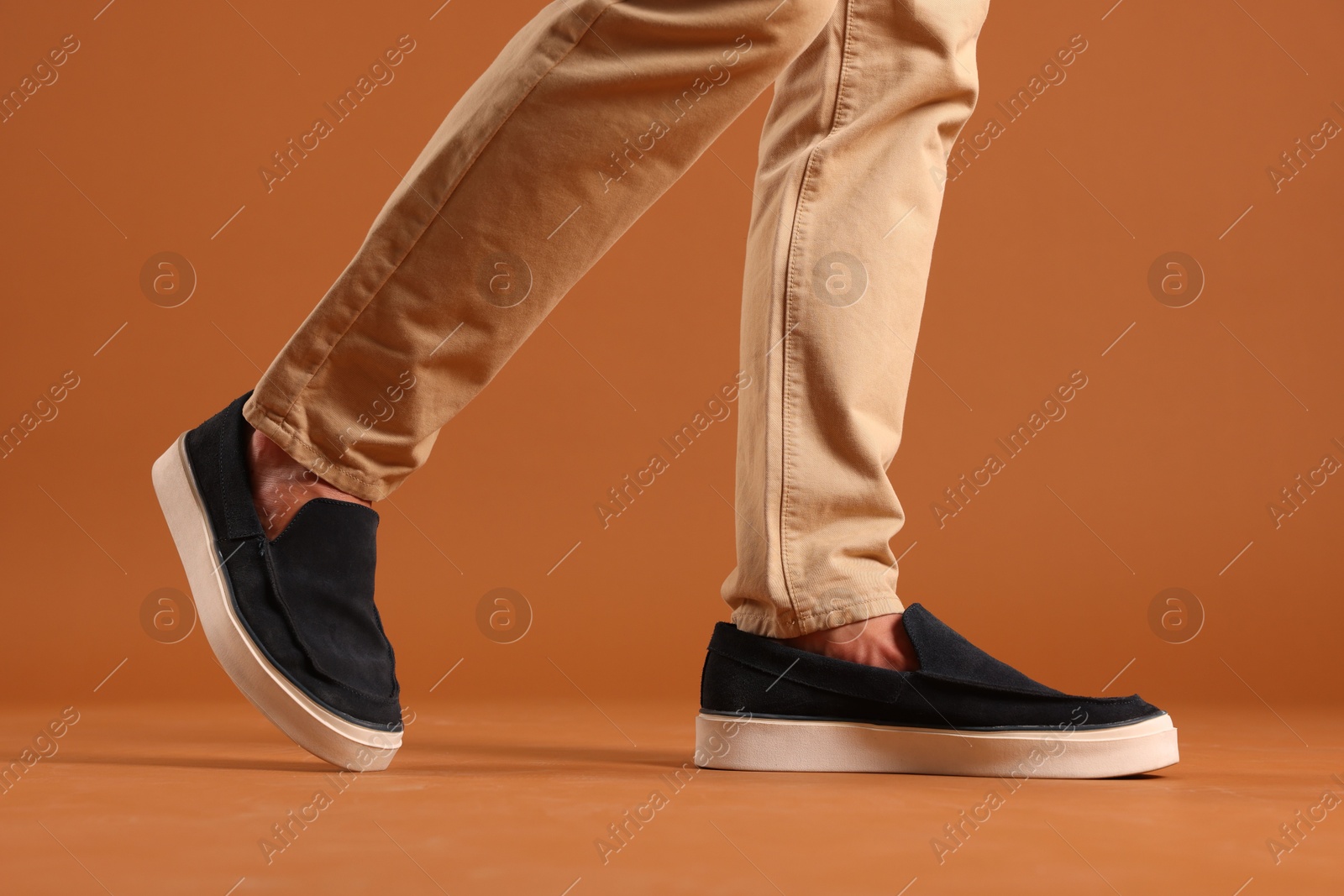 Photo of Man wearing pair of dark blue shoes on brown background, closeup
