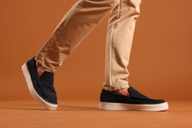 Photo of Man wearing pair of dark blue shoes on brown background, closeup
