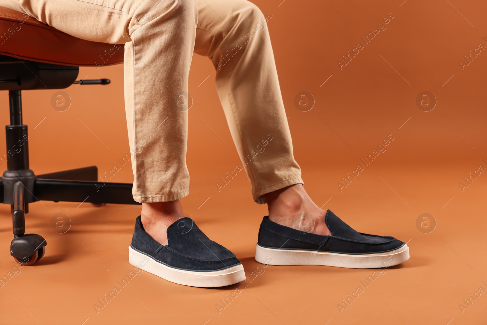 Photo of Man wearing pair of dark blue shoes on brown background, closeup