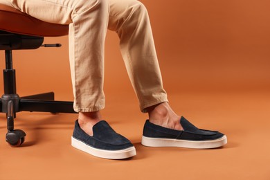 Photo of Man wearing pair of dark blue shoes on brown background, closeup