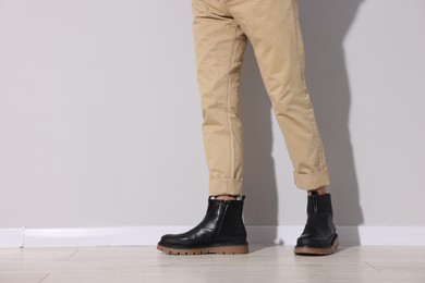 Photo of Man wearing pair of boots indoors, closeup. Space for text